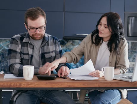 A couple working on their finances together at home, showing teamwork and collaboration.